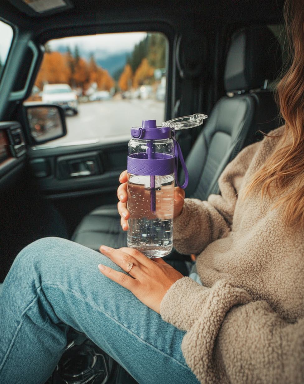 Woman holding an OTOO water bottle inside a car on a road trip