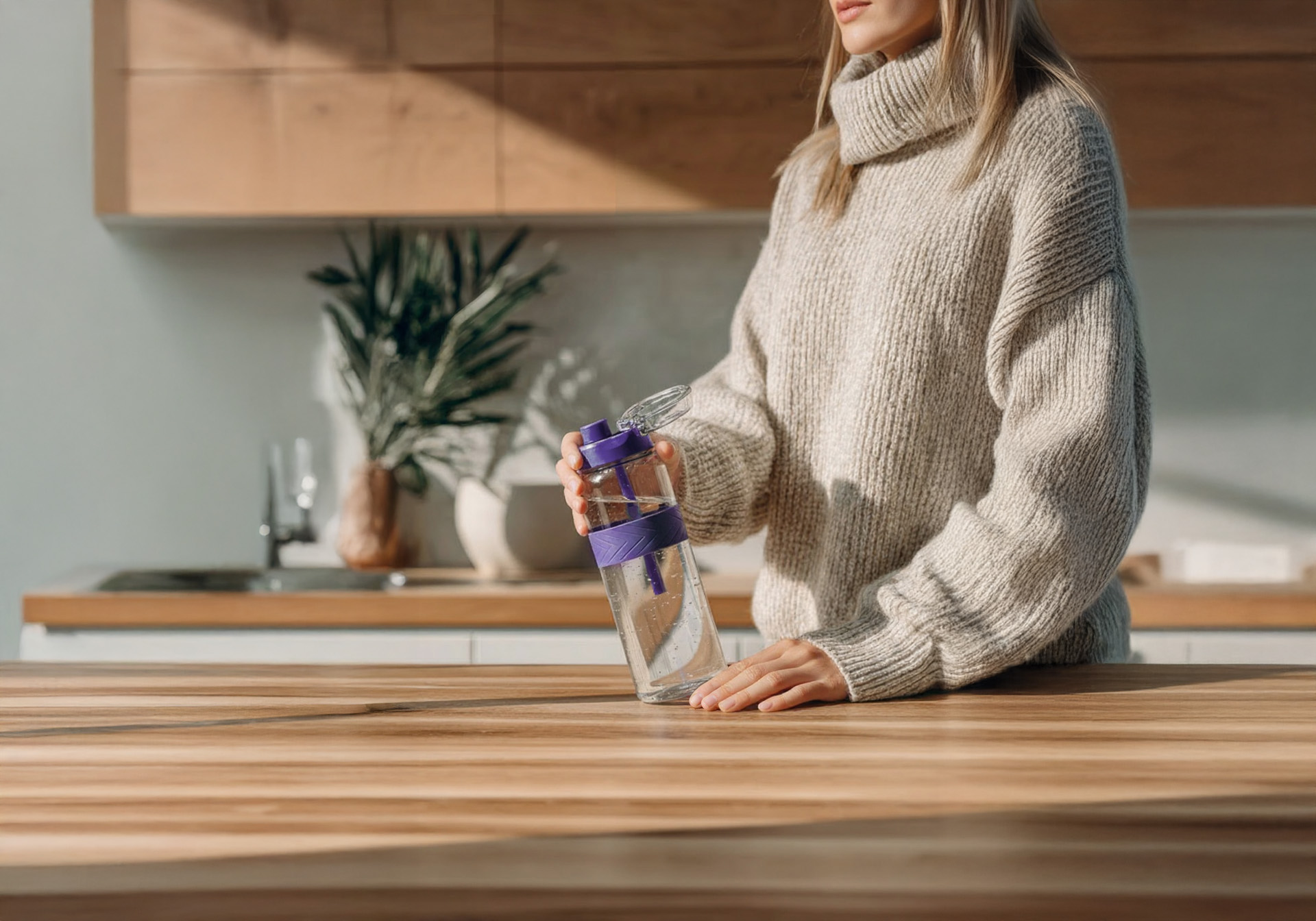 Woman holding an OTOO water bottle in her kitchen